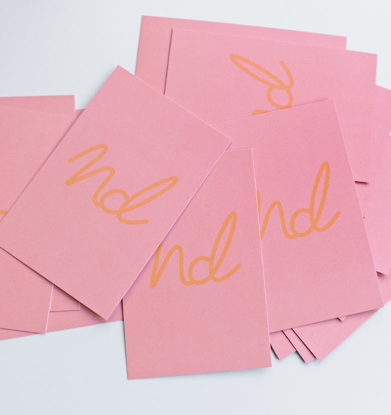 Stapel von rosa Visitenkarten mit gelbem 'nd' Logo und Wellenform. 